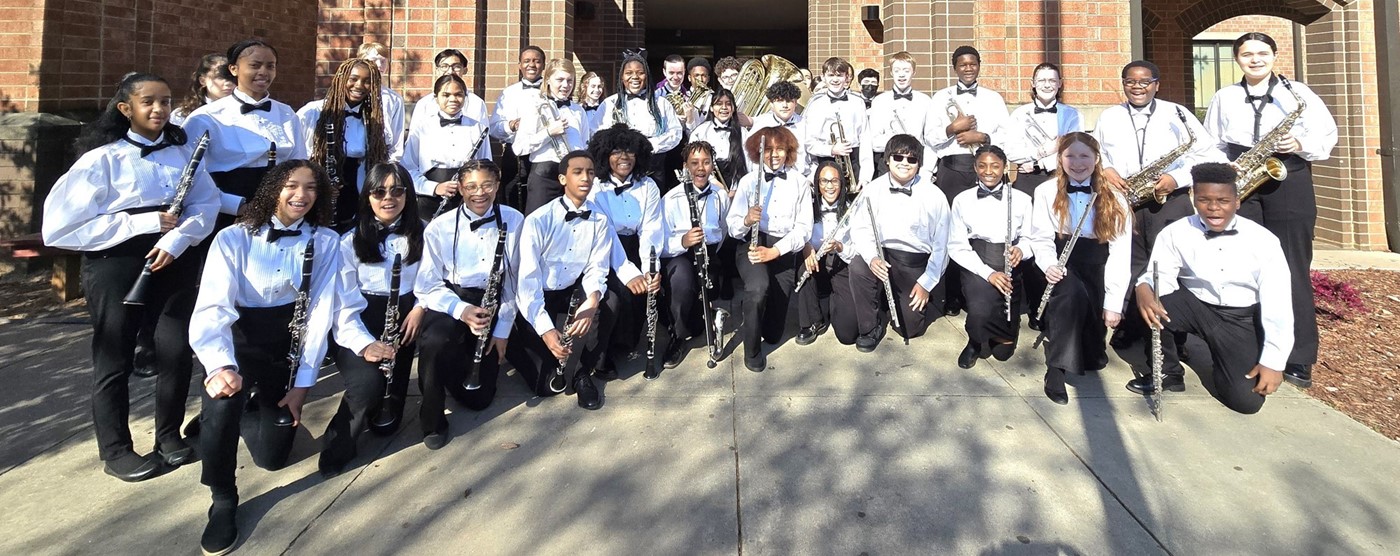 7th and 8th grade band students pose in front of the school after receiving a Superior (I) rating at LGPE